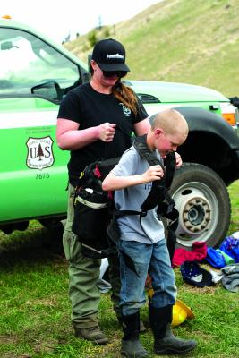 USFS Madison Ranger District fire crew member Sarah Rife, helps Sheridan third grader David Reeves try on a typical wildfire fighter’s field backpack at Bear Creek Days Tuesday, May 14. (H. Kearse)