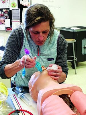 Jane Oakes practices inserting an adjunct airway on a mannequin, a device is used on an unconscious patient.
