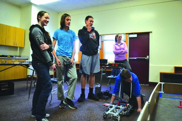 Trista Redfield, C. J. Wayland, and Matthew Kaiser and coach Jennifer Elser look over Ethan Wayland’s work with robotics in the competition space