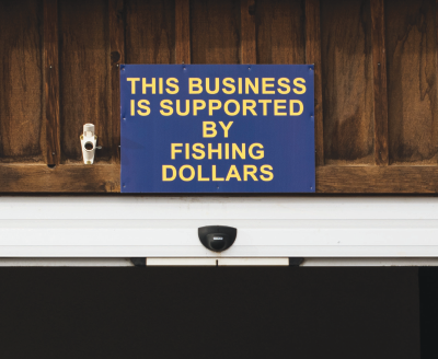 Sign over the entrance of the Madison Foods grocery store, indicating a prioritization of fishing in Ennis’ economy Dec. 21. “It’s not to diminish ag dollars that come here,” store owner Chris Gentry said. “This is just about what’s happening right now.” PHOTO BY HANNAH KEARSE