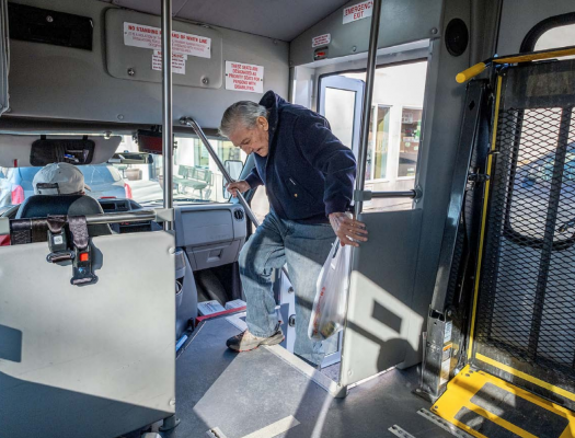 After shopping at The Corner Store, Whitehall resident Bruce Ball boards a Whitehall Public Transportation bus driven by LeRoy Murphy Feb. 21, 2020. (Ball has since passed away.) PHOTO BY JOHN BLODGETT, BOULDER MONITOR