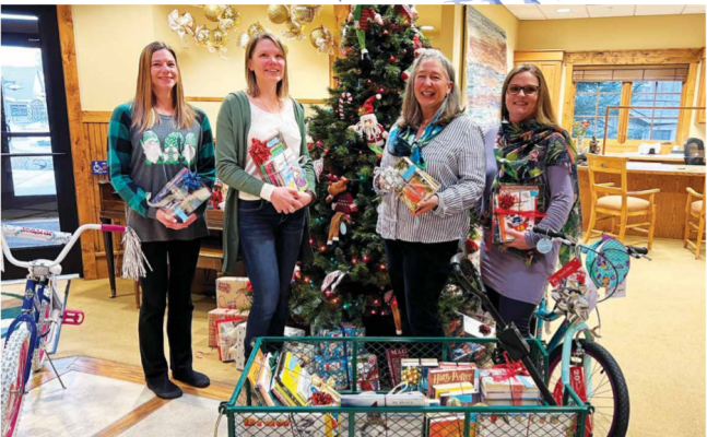 (L to R) Anne Olson, Coordinator of the Madison Valley Bank Giving Tree, Bayley Gibson, Youth Services Specialist at Madison Valley Public Library, Karen Ketchu, Madison Valley Public Library Director and Andrea Noack, Assistant Operations Manager at Madison Valley Bank, coordinated to help bring the magic of books to kids across the valley for Christmas this year. PHOTO BY CORI KOENIG
